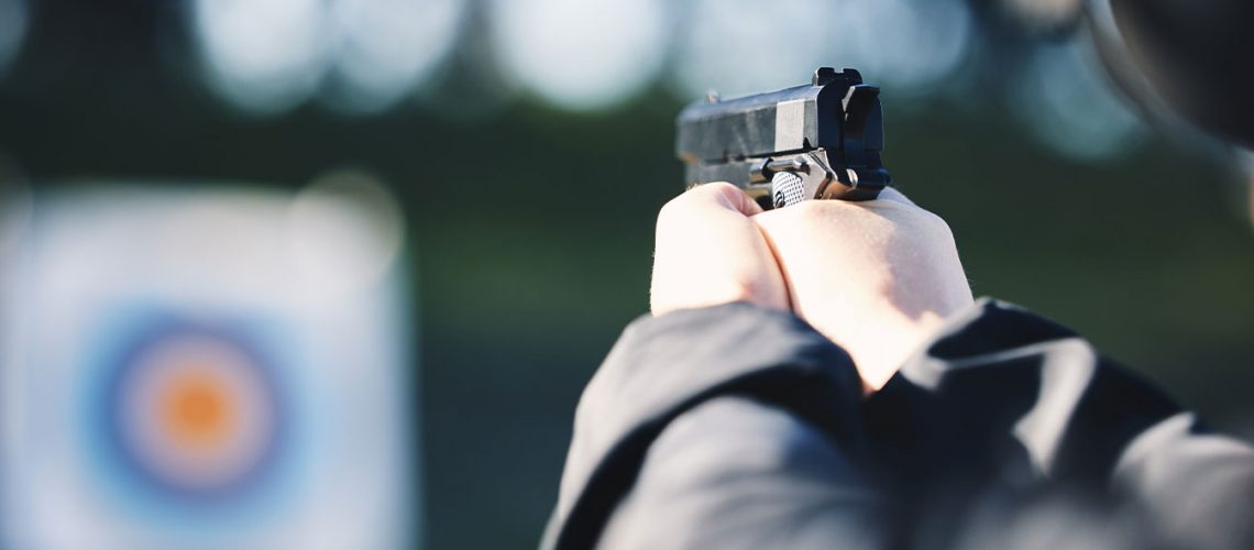 Someone firing a pistol at a target on a shooting range